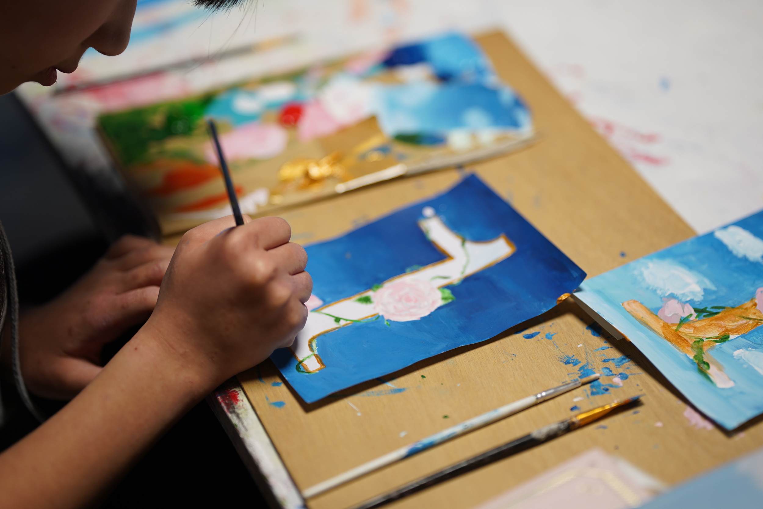 爆発芸術舎（ばくげい）のポスター作品完成に向けて色塗りしている子ども